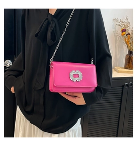 Detailed view of fuchsia leather crossbody bag with sparkling diamond buckle and silver chain