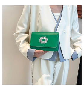 Detail of green square chain bag with crystal buckle on model wearing light blue suit