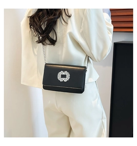 Detail of black matte leather shoulder bag featuring a large square rhinestone buckle