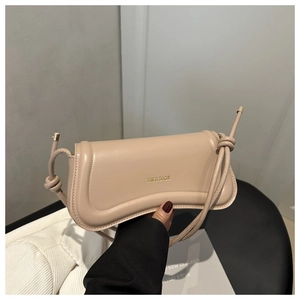 Close-up of beige leather bag detail with wave-shaped flap and gold XM & BAGS text