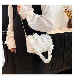 Detail of white pleated shoulder bag with large bow and golden chain strap for women