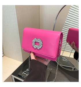 Detail of rose pink crossbody bag featuring a large square rhinestone buckle and silver chain