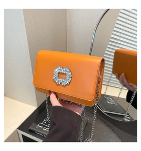 Detail of bright orange bag with sparkling crystal buckle and silver chain strap