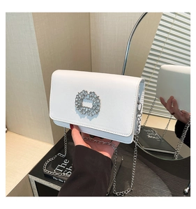 Detailed macro view of white square flap bag with large sparkling round rhinestone buckle