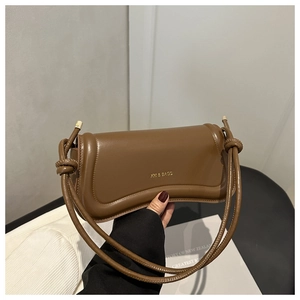 Detailed close-up of brown leather shoulder bag with decorative strap knot and gold logo