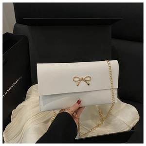 White envelope bag with gold bow clasp and metal chain strap in premium gift packaging