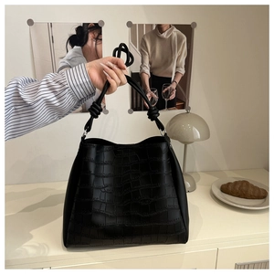 Dettaglio della borsa nera con goffratura coccodrillo e manico con nodo decorativo