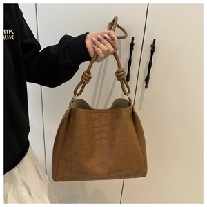 Dettaglio ravvicinato della borsa hobo marrone con texture coccodrillo e tracolla a nodo