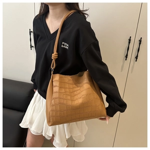 Dettaglio di una borsa tote marrone con trama a coccodrillo e nodo decorativo sulla tracolla