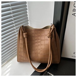 Dettaglio borsa tote marrone motivo coccodrillo con tracolla decorativa a nodo
