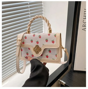 Close-up of strawberry print handbag featuring a golden swivel lock and braided handle