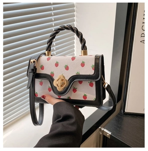 Detail of the strawberry print small square bag with woven handle and gold floral lock