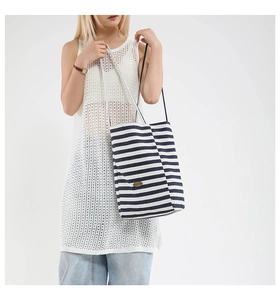 Detail of blue and white striped canvas tote with brown leather patch and woven texture