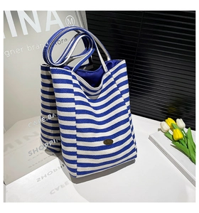 Close-up of blue and white striped tote bag with elegant metal plate and canvas texture