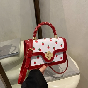 Chic strawberry print crossbody bag with red braided handle and gold floral clasp