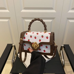 White leather handbag with red strawberry prints, twisted handle and golden flower lock