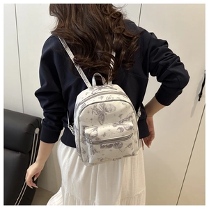 Rear view of a mini cream butterfly print backpack worn with a white pleated skirt
