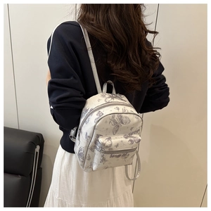 Detailed back view of a mini cream backpack with artistic grey butterfly and floral prints