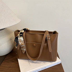 Brown faux leather tote bag with white contrast stitching and a silk scarf handle detail