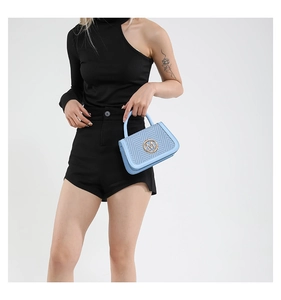 Dettaglio borsa intrecciata azzurra con logo M dorato e finiture in pelle su modella