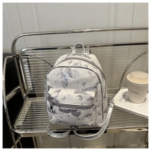 Close-up of mini backpack featuring silver butterfly prints and metallic silver straps