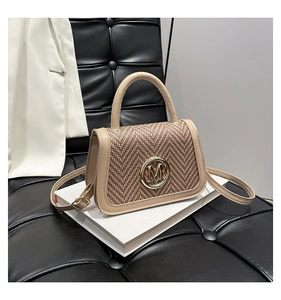 Dettaglio di una piccola borsa beige testurizzata con logo M dorato e manico superiore