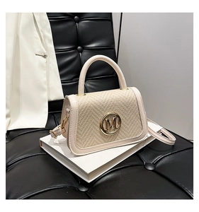 Dettaglio della borsa in pelle crema e paglia con logo M dorato e finiture in metallo