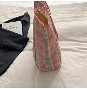 Detail of pink plaid canvas tote bag next to a blazer and book in a lifestyle setting