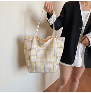 Fashion model wearing a large plaid nylon tote bag in yellow and grey checkers