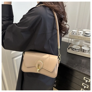 Side view of a woman wearing a chic beige shoulder bag with a gold horseshoe buckle