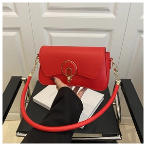 Detalle de bolso cuadrado rojo con hebilla dorada circular y cadena de la correa