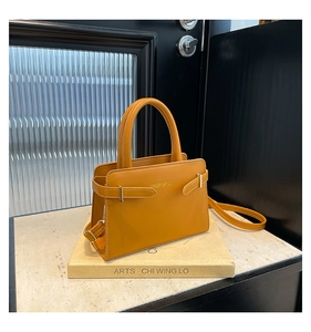 Detail van de gele lederen handtas met metalen gespen aan de zijkant en verstelbare riem