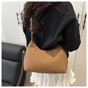 Brown woven hobo bag with crescent shape and fine texture worn as a shoulder bag
