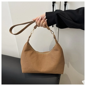 Close-up of the brown woven texture and gold metal clips on a minimalist tote bag