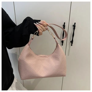 Detail of pink half-moon bag featuring diagonal striped texture and gold-tone metal hooks