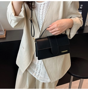 Close-up of black matte leather square bag with Fashion text on beige blazer outfit