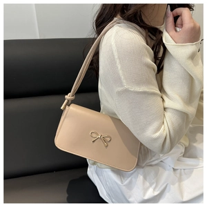 Dettaglio borsa a tracolla beige crema con fibbia a fiocco dorato e cinturino annodato