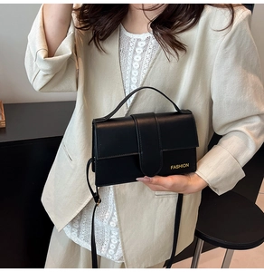Fashionable black matte crossbody bag with top handle and golden brand logo detail