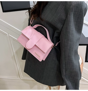 Detail of light pink crossbody bag with a fashion logo worn by a stylish model