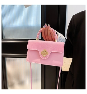 Detailed shot of pink handbag featuring a gold floral lock and woven handle held by a model
