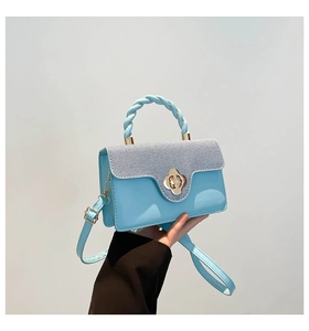 Close-up of light blue small square bag with golden flower lock and woven handle