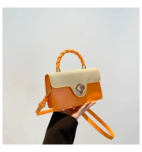 Detail of orange patent leather handbag with woven flap and gold flower buckle clasp