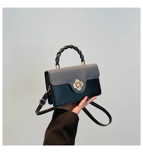Detail of bicolored crossbody bag featuring grey fabric flap and golden petal clasp