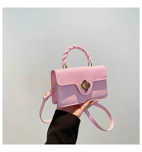 Detail of light pink square bag showing fabric texture, flower clasp, and woven handle