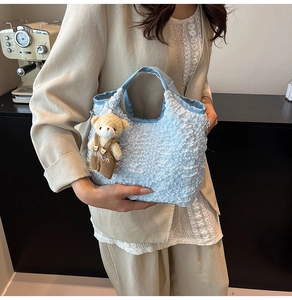 Detail of light blue pleated bucket bag featuring a cute brown bear doll charm
