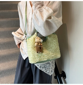 Detail of light green ruched bucket bag with cute teddy bear charm and crossbody strap