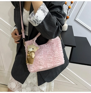 Detail of pink pleated bucket bag with cute teddy bear charm and golden metal hardware