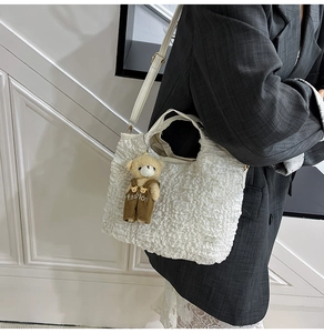 Detailed texture of white pleated bucket bag featuring a cute brown bear charm accessory