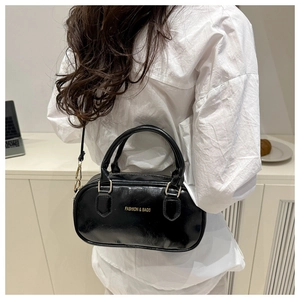 Detail of glossy black Boston bag with gold FASHION & BAGS logo and crossbody strap