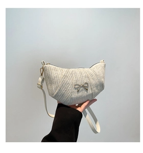 Detailed view of woven crescent bag with gold bow buckle and adjustable leather strap